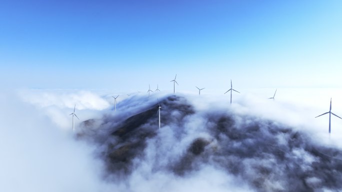 蓝色天空下云雾中高山上的风力发电机组