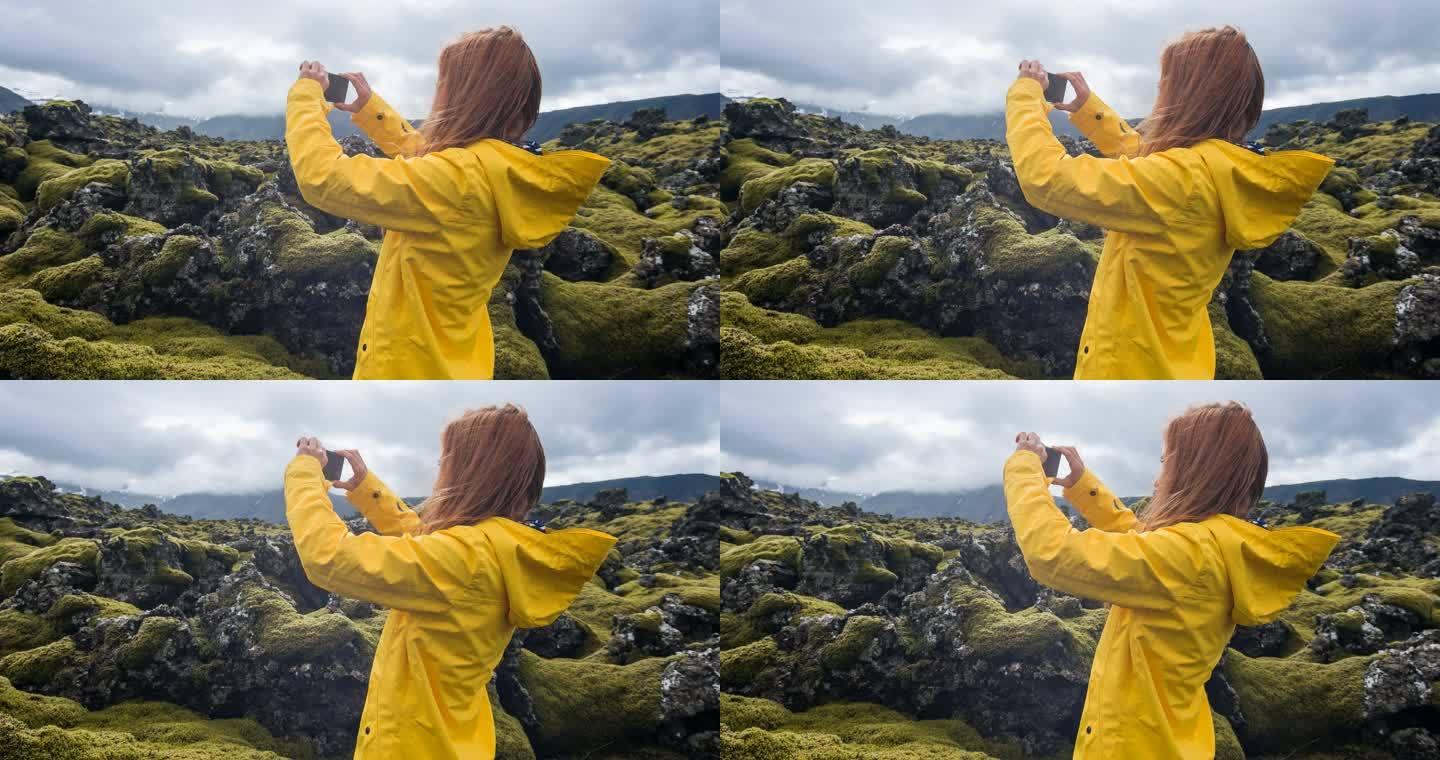用智能手机拍摄冰岛岩石和苔藓景观的女人