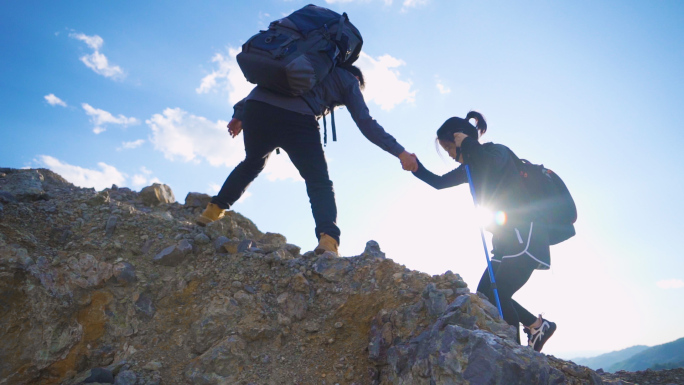 一男一女手拉手登山逆光人物攀登顶峰旅行者