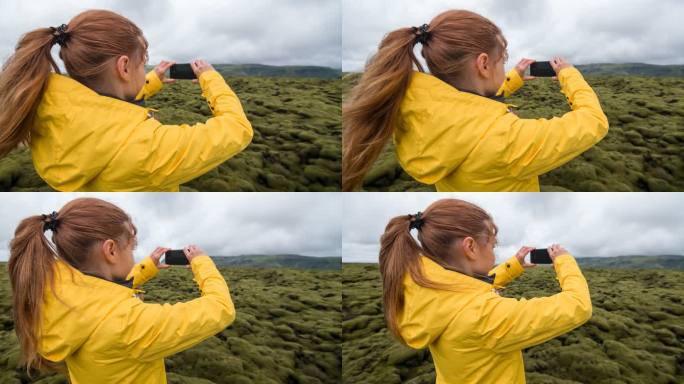 身穿黄色雨衣的女子在苔藓覆盖的熔岩场拍照