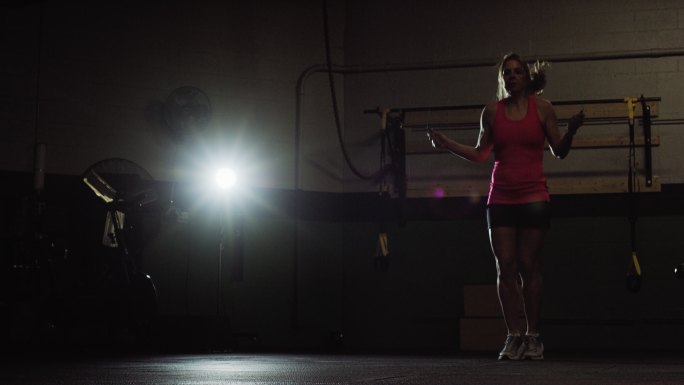 一名40多岁的高加索女子在室内健身房穿运动服跳绳的慢镜头