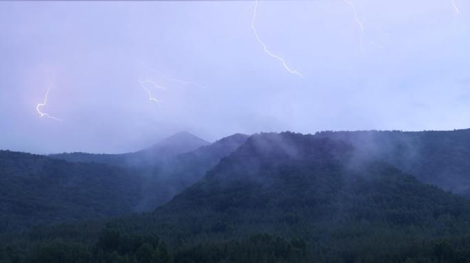 山村一边打雷下雨一边腾起云雾和雨后的彩虹