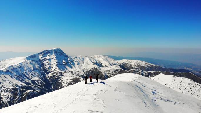 冬季成功登山队在高海拔雪山山顶张开双臂的无人机鸟瞰图