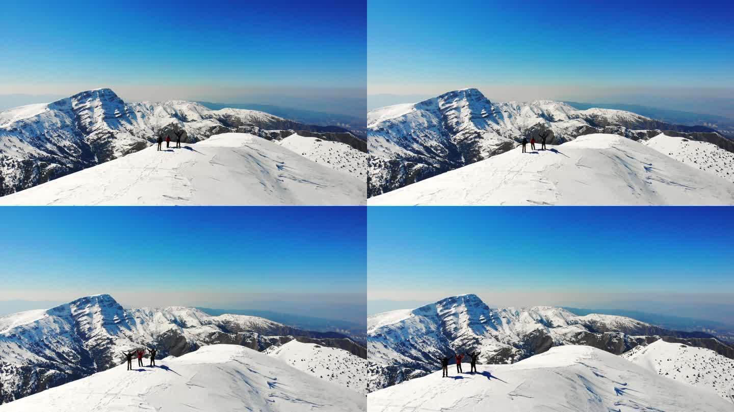 冬季成功登山队在高海拔雪山山顶张开双臂的无人机鸟瞰图