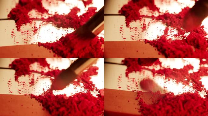 用刷子将红色粉末腮红刷得粉碎。工作室拍摄，镜像背景