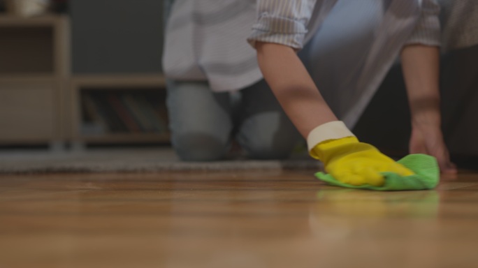 穿着黄色手套的家庭主妇坐在清洁室地板上，铺有纤维布