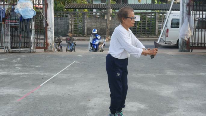 老年女子在停车场练习中国剑舞