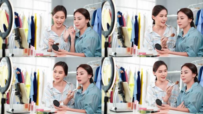 两位美丽的亚洲年轻博主在社交网络上直播视频，销售化妆品，并建议如何用化妆刷在脸颊、额头和鼻子上薄薄地