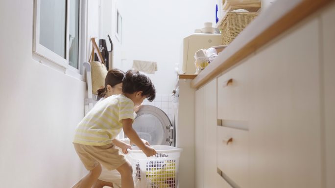 男孩和年轻的母亲把衣服放入洗衣机