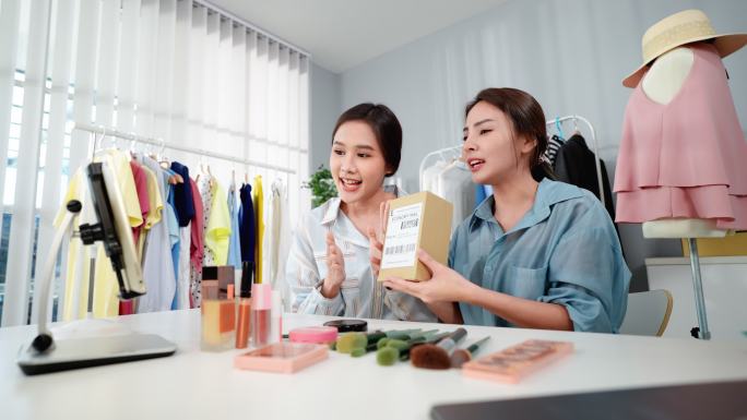 两名从事化妆品在线销售的亚洲年轻女性中小企业正在向购买成套刷子的顾客或追随者赠送礼品套装。两个年轻漂