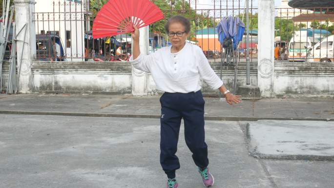 老年妇女在停车场练习中国手扇舞