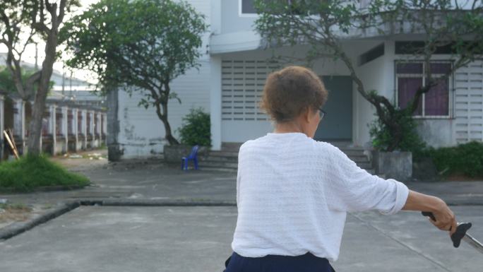 老年女子在停车场练习中国剑舞