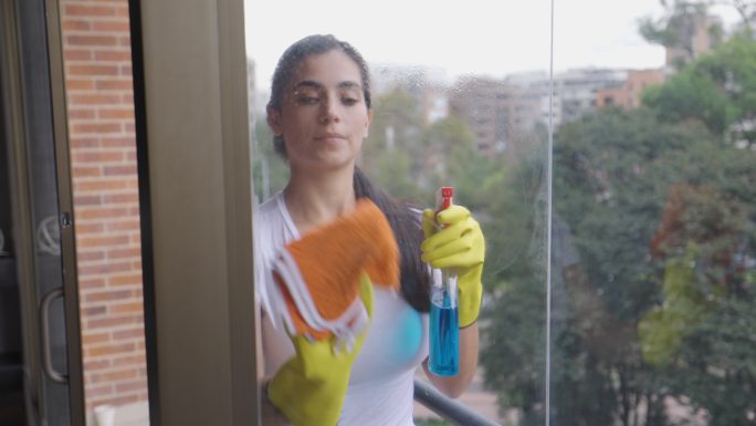 美丽的拉丁美洲妇女在家里擦窗户