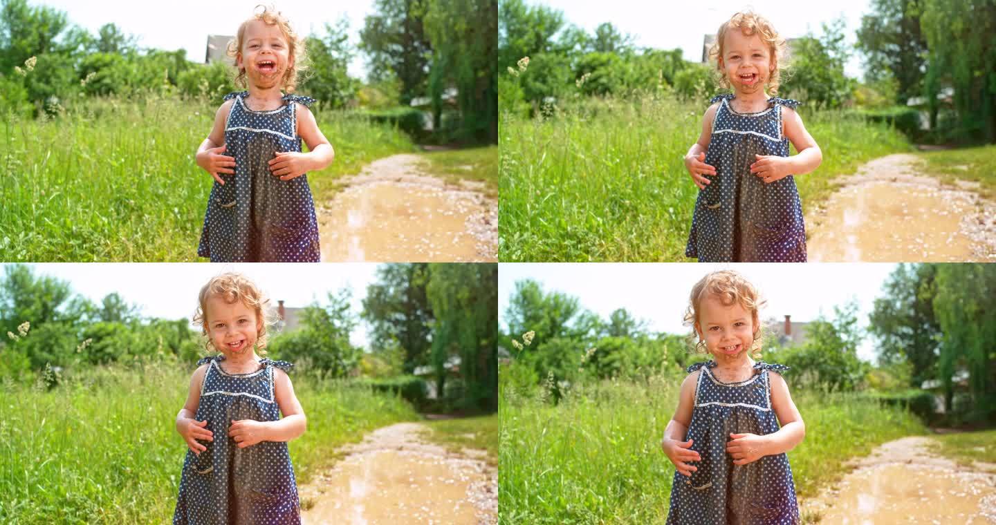 SLO MO小女孩穿着一件脏兮兮的衣服，身上沾满了泥土，她在镜头前笑着掉进了水坑