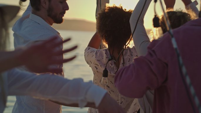 SLO MO朋友们在日落时在船的甲板上跳舞