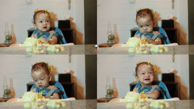 一名男婴在第一次生日派对上，脸上和身上都沾满了生日蛋糕的残留物