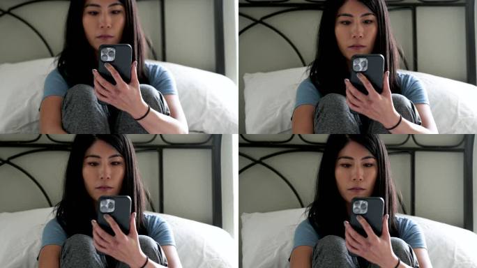 亚洲家庭主妇坐在床上使用智能手机