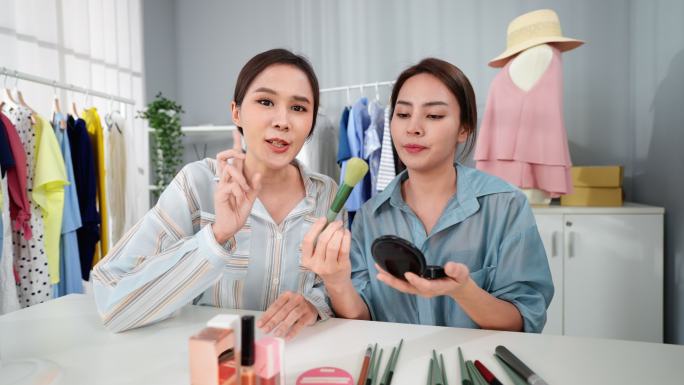两位亚洲女性博客写手正在家里用相机评论她们的扑面粉产品。美丽的美妆博主Influencer女孩正在直