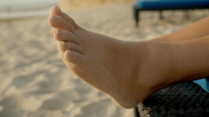 男孩的脚套，沙滩椅上的沙子晃动，生活方式理念。