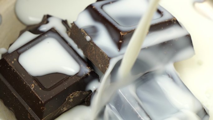 牛奶巧克力溅到巧克力块上，巧克力块上的牛奶被倒入固体巧克力上