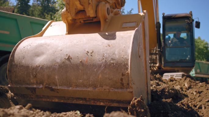 SLO MO挖掘机铲斗在阳光下在施工现场挖掘土壤
