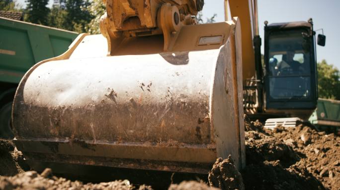 SLO MO挖掘机上的铲斗在阳光下挖掘土壤并填充