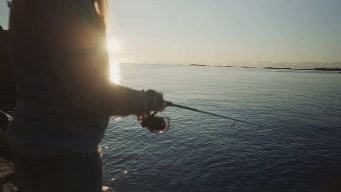 挪威户外：一名妇女用鱼竿在海里钓鱼