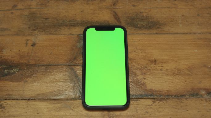 木制桌子上的绿色屏幕电话