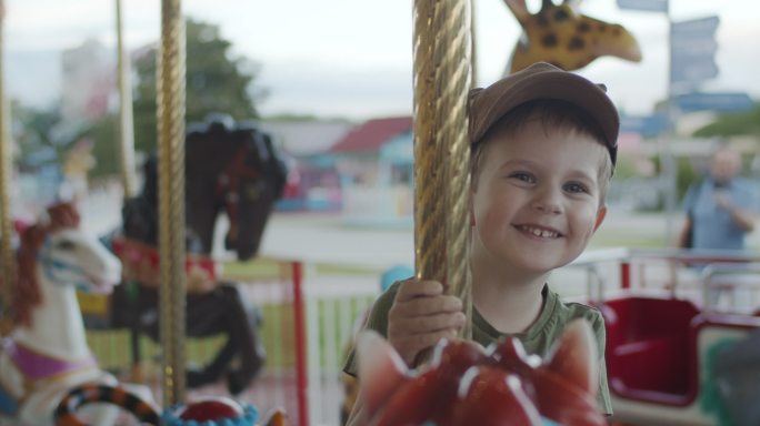 可爱的小男孩在游乐场享受旋转木马