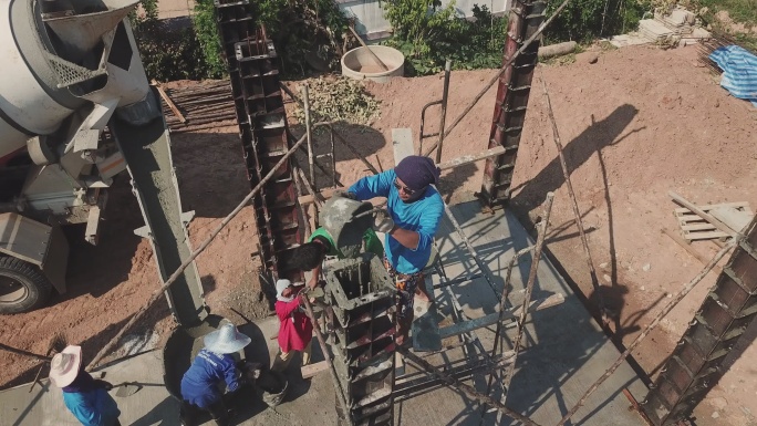 鸟瞰图。建筑工人在一个小型工地将混凝土泵入水泥柱模板。