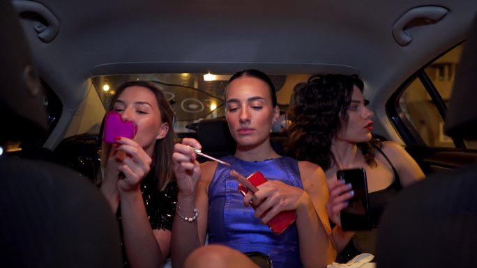 三名女性在参加派对时在汽车后座化妆