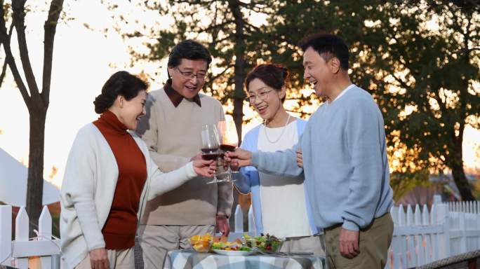 夕阳下中老年朋友在庭院里聚会喝酒干杯