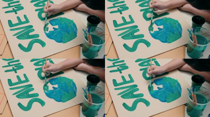 特写志愿者儿童制作海报“拯救地球”