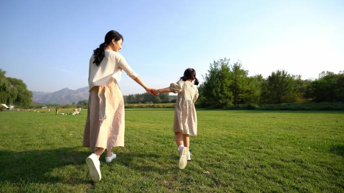 妈妈和女儿在草地上奔跑玩耍