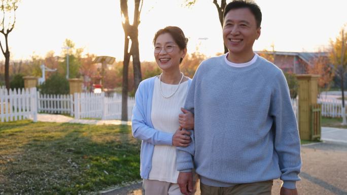 夕阳下中老年夫妻手挽手在露营地聊天散步