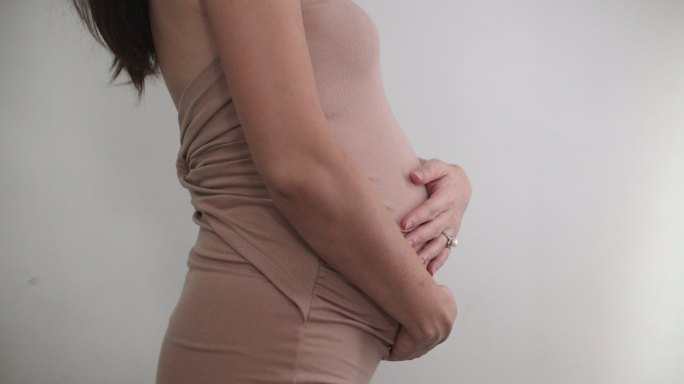 亚洲孕妇用手触摸和抚摸孕肚
