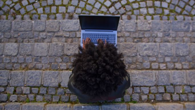 城市里坐在楼梯上使用笔记本电脑的年轻女子