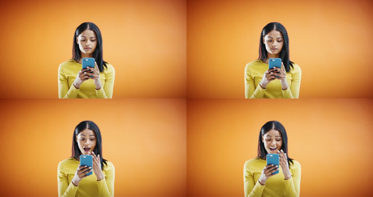 4k视频画面显示，一名年轻女子使用智能手机，在橙色的摄影棚背景下看起来很震惊