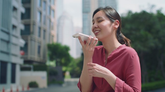 亚洲女子在社交网络中与智能手机语音助手通话，为公园里的朋友