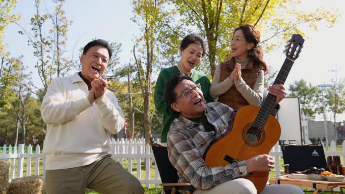 中老年人在房车露营院子里聚会弹吉他唱歌