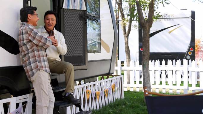 中老年人在房车露营地喝啤酒聊天看手机视频