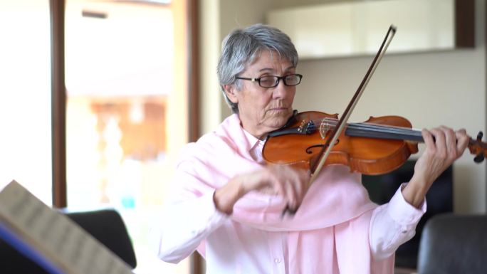 在家拉小提琴的老年妇女