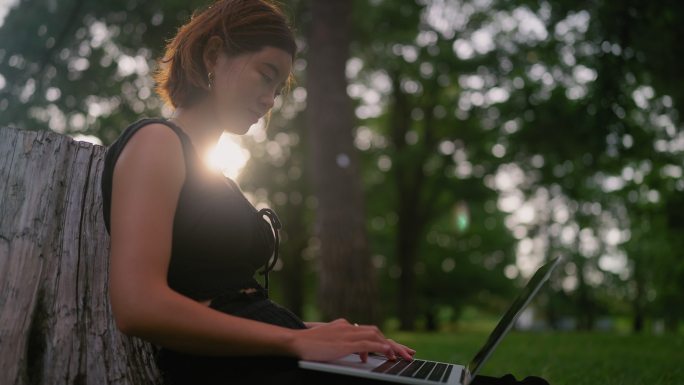 年轻女性在大自然中放松，使用笔记本电脑