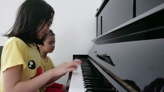 两个亚洲中国女孩一起在家玩钢琴