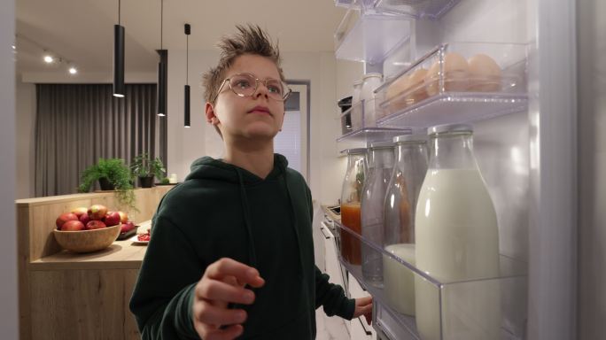 十几岁的男孩从冰箱里取出柠檬。
