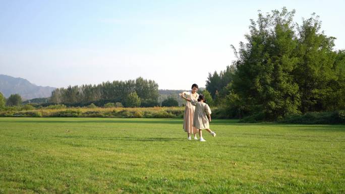 妈妈和女儿在草地上转圈玩耍
