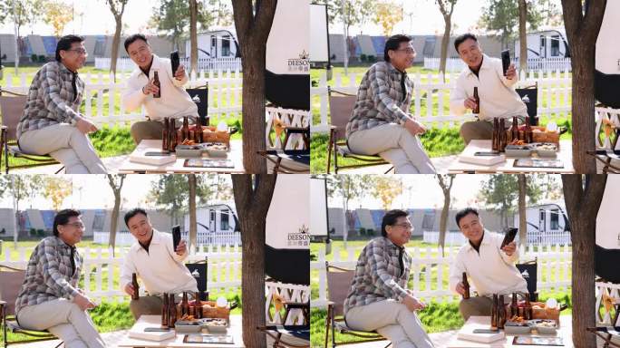 两个老年男人坐在房车露营院子里看手机视频