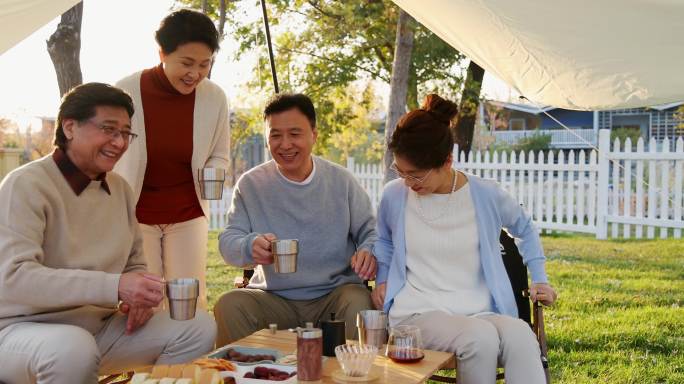 一群中老年人露营地天幕下喝咖啡合影