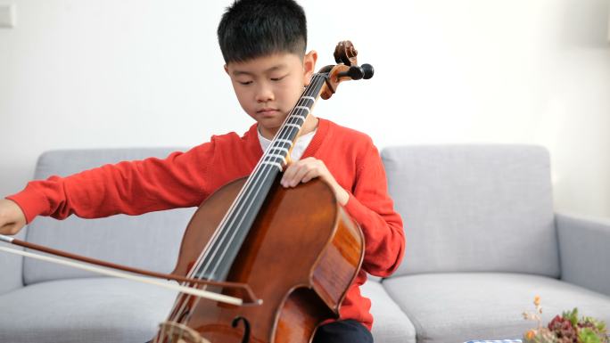 一个在家练习大提琴的小男孩