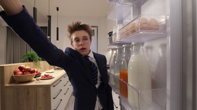 从学校回来的十几岁男孩从冰箱里拿着一顿饭。